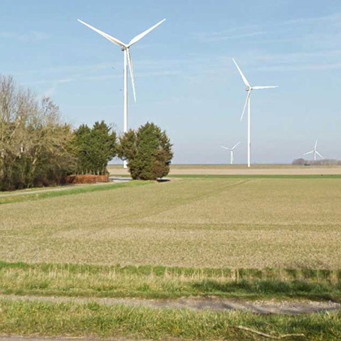 A landscape featuring several wind turbines in a flat field under a clear blue sky.