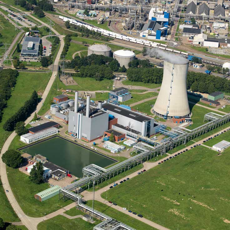 Aerial view of an industrial complex featuring cooling towers, storage tanks, and interconnected pipelines.