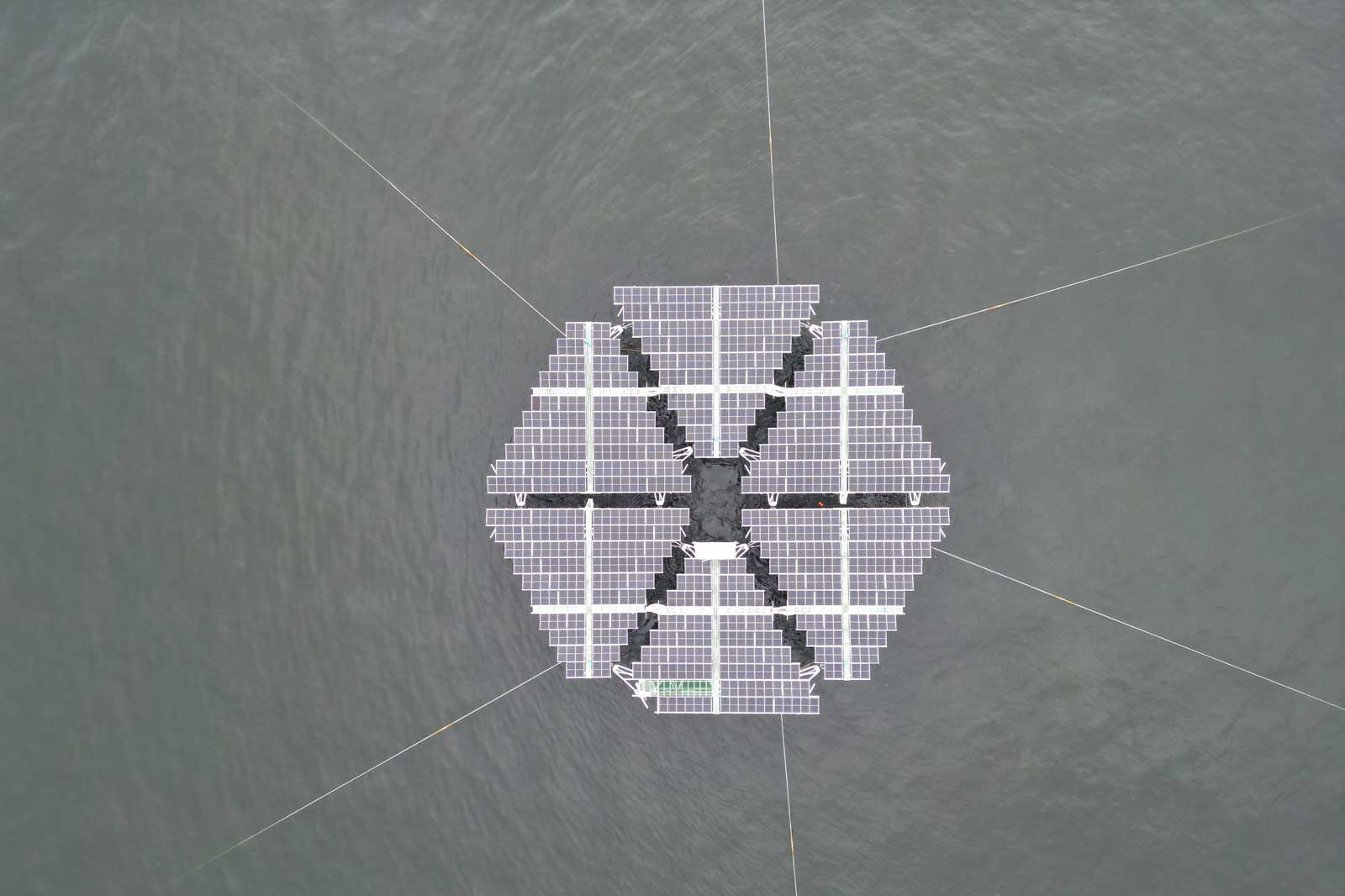 Een drijvende zonne-energie-installatie in een hexagonaal patroon op kalm water.