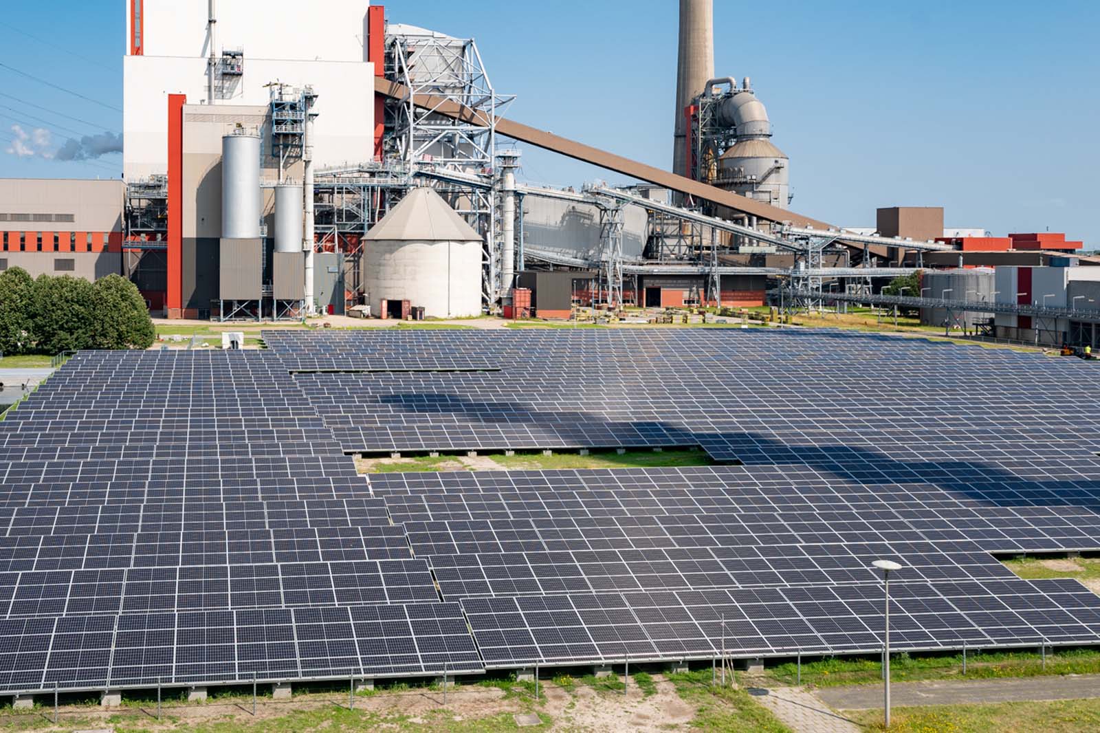 Een zonnepaneelarray voor een industrieel gebouw, die de integratie van hernieuwbare energie met machines op de achtergrond toont.