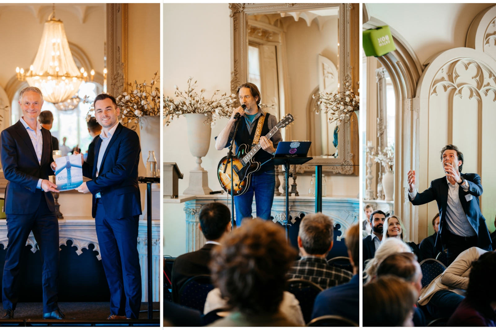 A musician performs with a guitar, microphone, and laptop on a stage decorated with elegant vases and flowers.