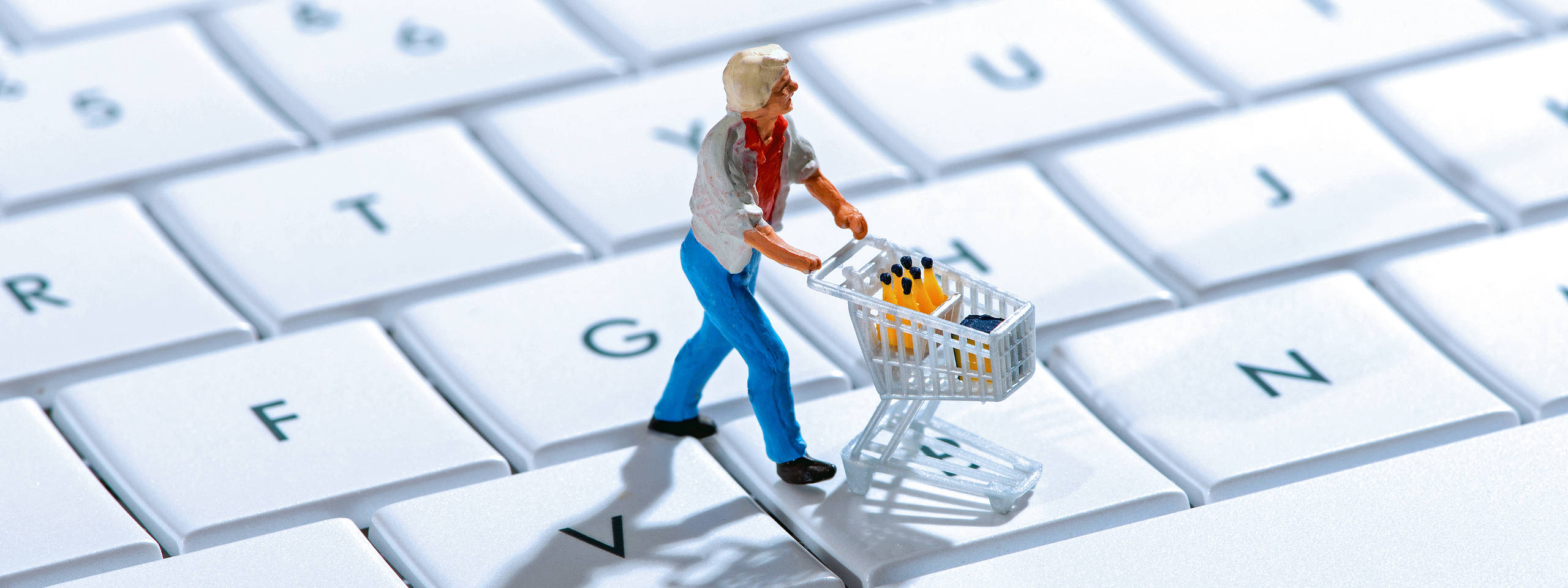 Een klein figuur met een winkelwagentje op een toetsenbord, omringd door witte toetsen.