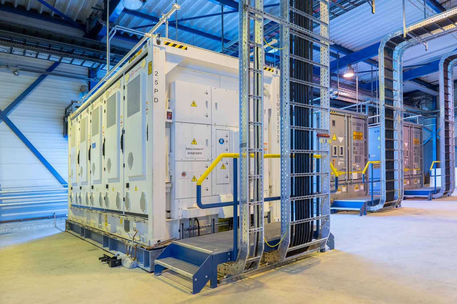 Een modern batterij systeem in een industriële omgeving met gele veiligheidsstappen en kabelgoten.